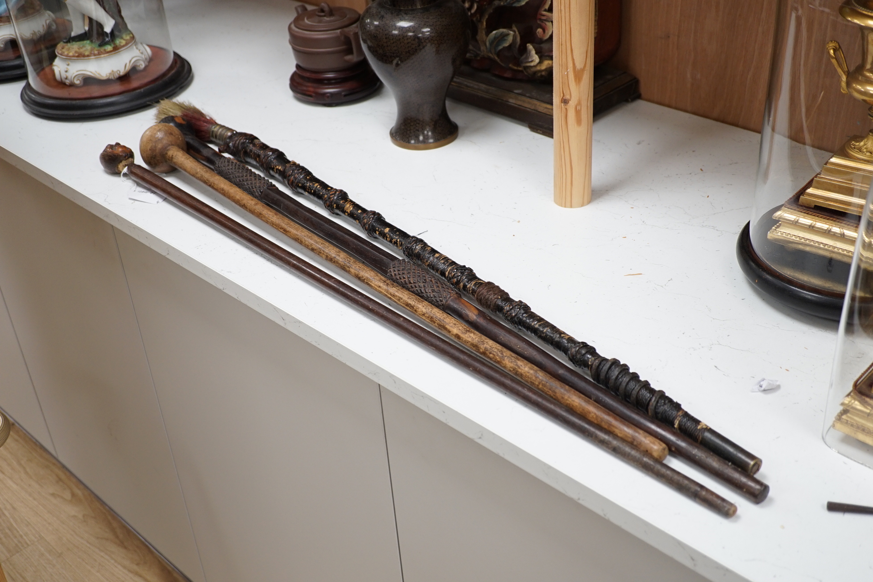 A ceremonial sword stick with removable brush end, a 19th century continental carved head with glass eyes on associated cane stick and two others, longest 93cm